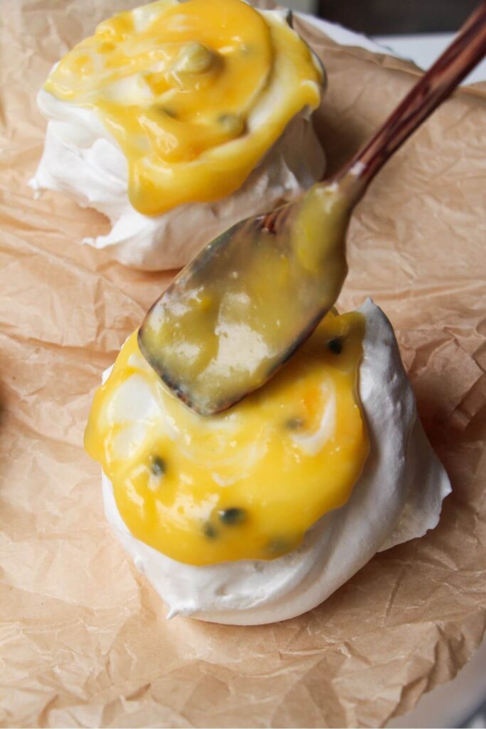 Wooden spoon topping mini pavlova with passionfruit curd.