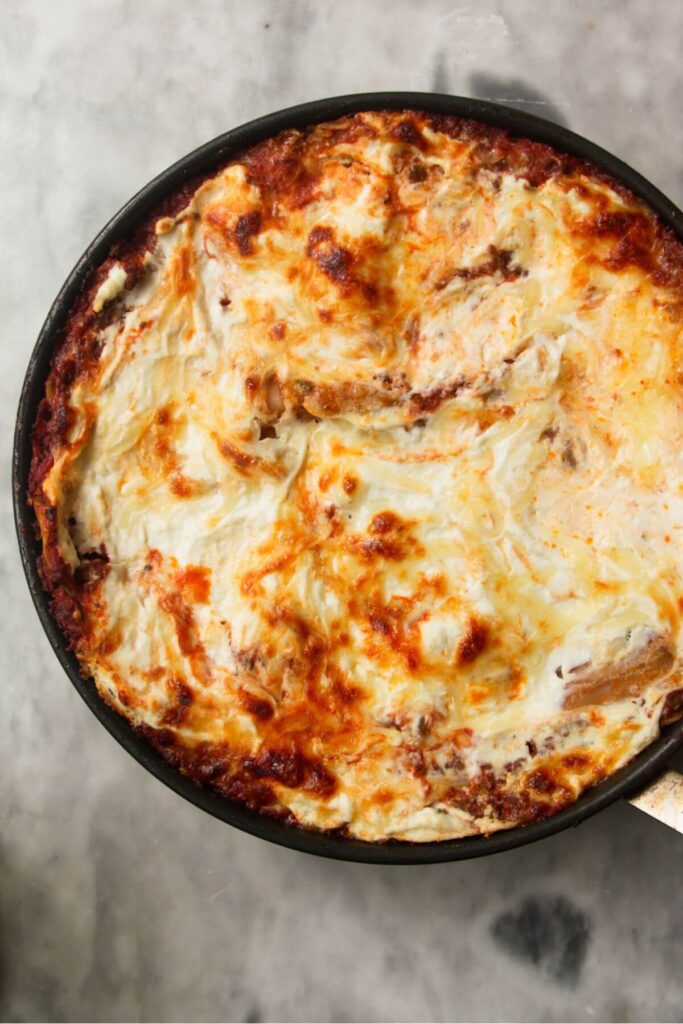 Golden, bubbling cheesy top to one pot lasagna in a small black pan.