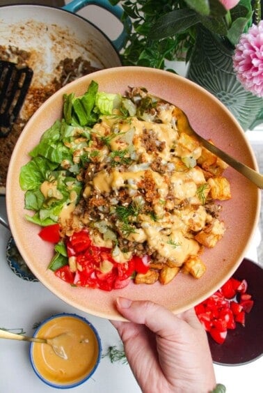 Holding loaded cheeseburger bowls drizzled with burger sauce.