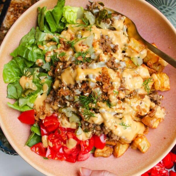 Holding loaded cheeseburger bowls drizzled with burger sauce.