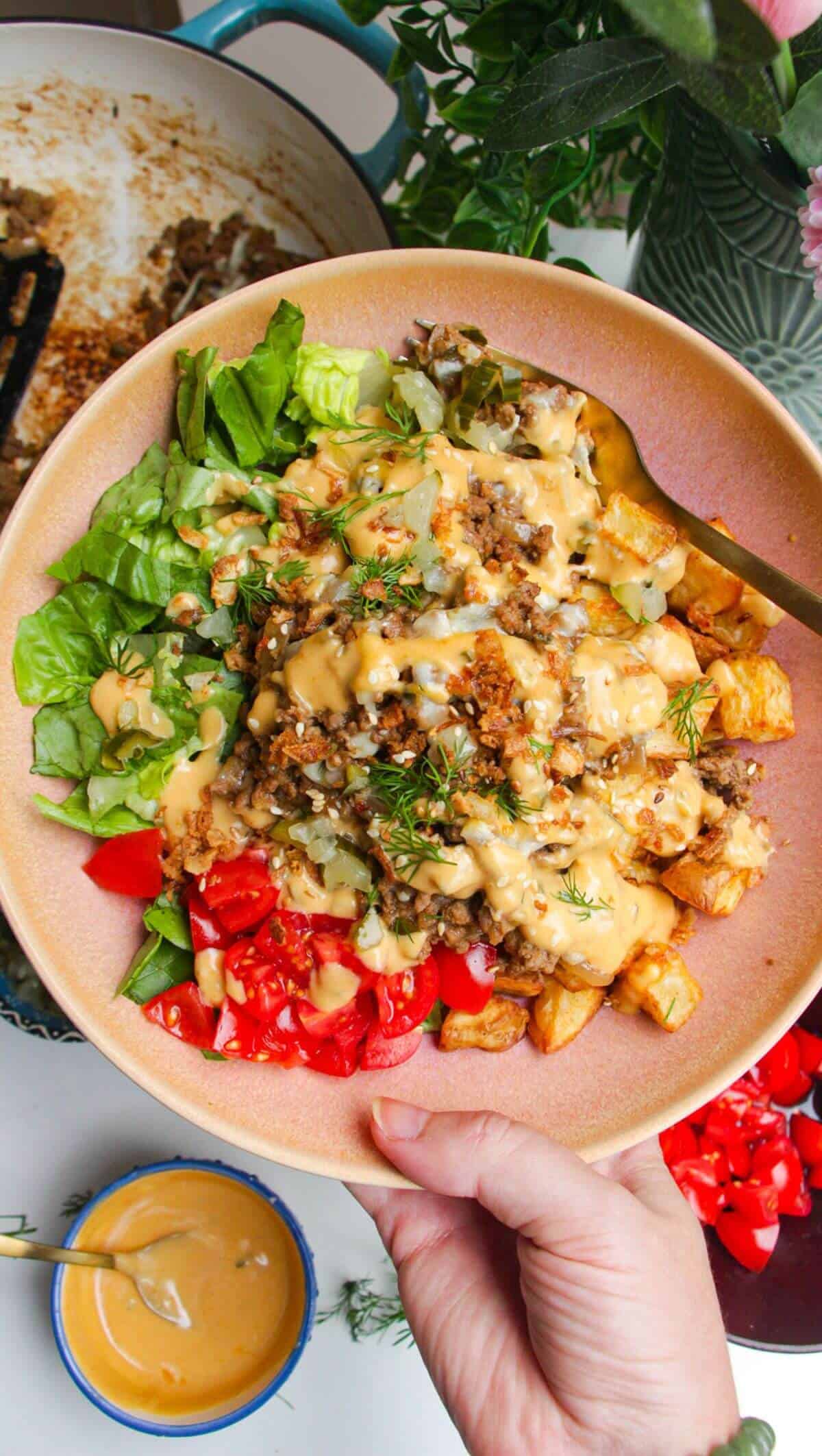 Holding loaded cheeseburger bowls drizzled with burger sauce.