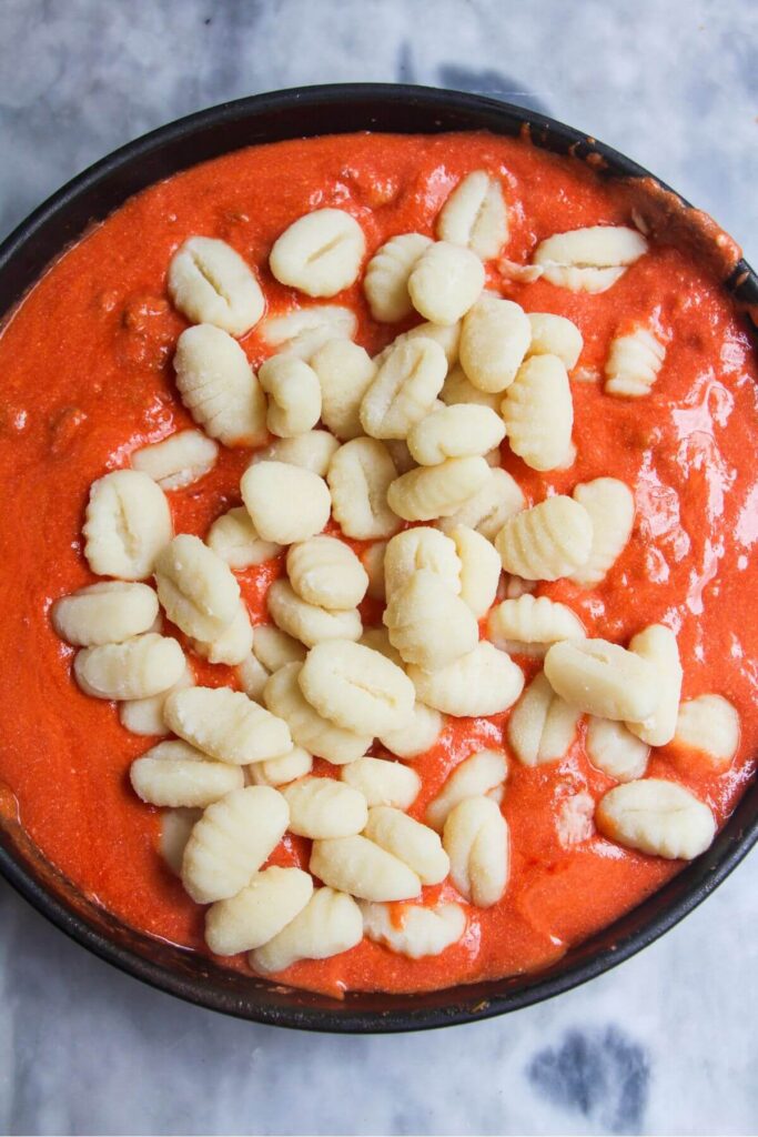 Gnocchi added to creamy tomato sauce in a pan.