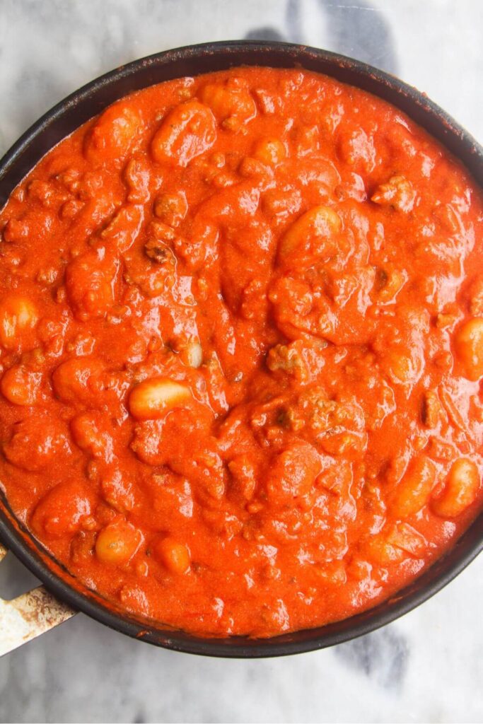 Gnocchi stirred through creamy tomato sauce in a pan.