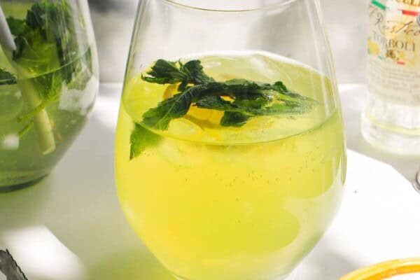 Limoncello spritz in a stemless wine glass with another spritz in the background.