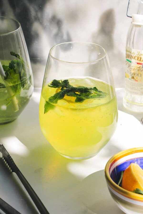 Limoncello spritz in a stemless wine glass with another spritz in the background.