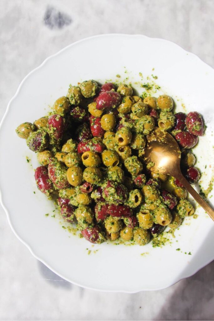 Pesto mixed through olives in a white bowl.