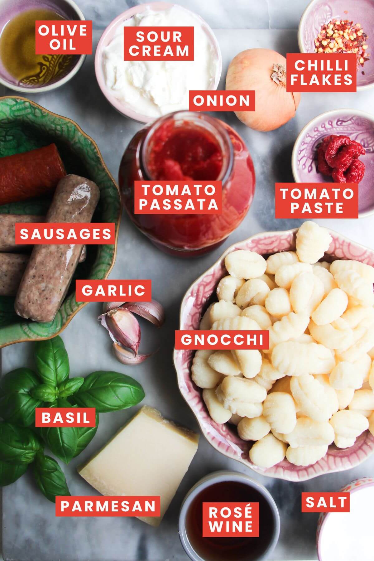 Ingredients for sausage gnocchi laid out on a bench and labelled.