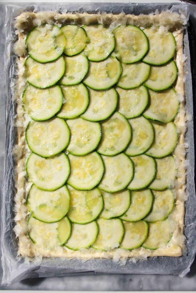 Thinly sliced zucchini layered on top of puff pastry with greated parmesan scattered on the crust.