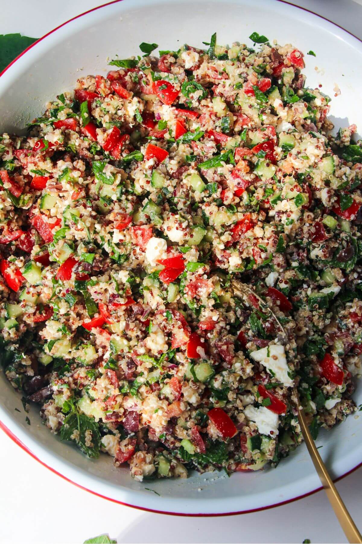 Greek quinoa salad mixed in a large white salad bowl.
