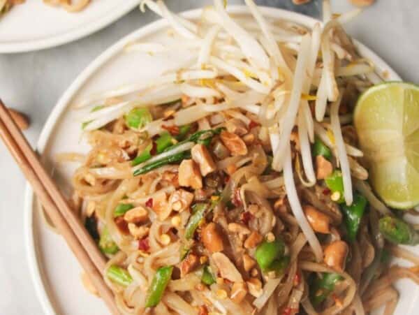 Two plates of pad thai on small white plates, with chopsticks on the side.