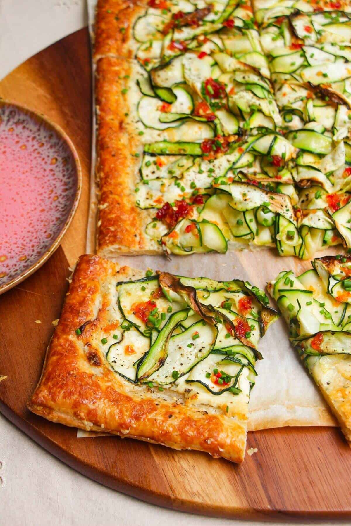 Zucchini and boursin tart on wooden board.