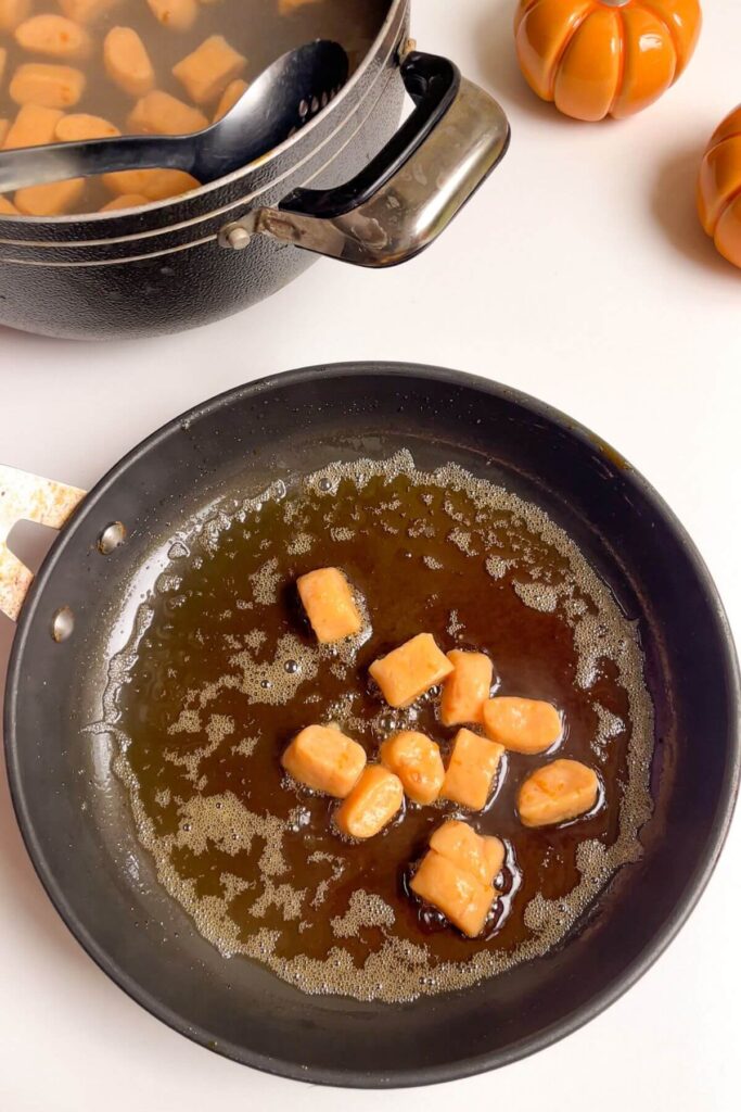 Sweet potato gnocchi in brown butter sauce in a small pan.