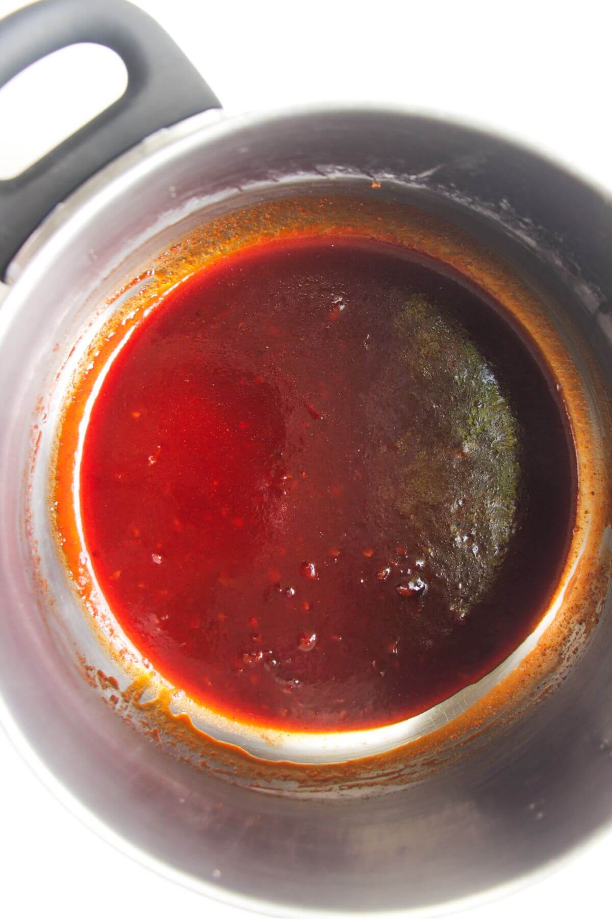 Sticky gochujang glaze in a small silver pot.