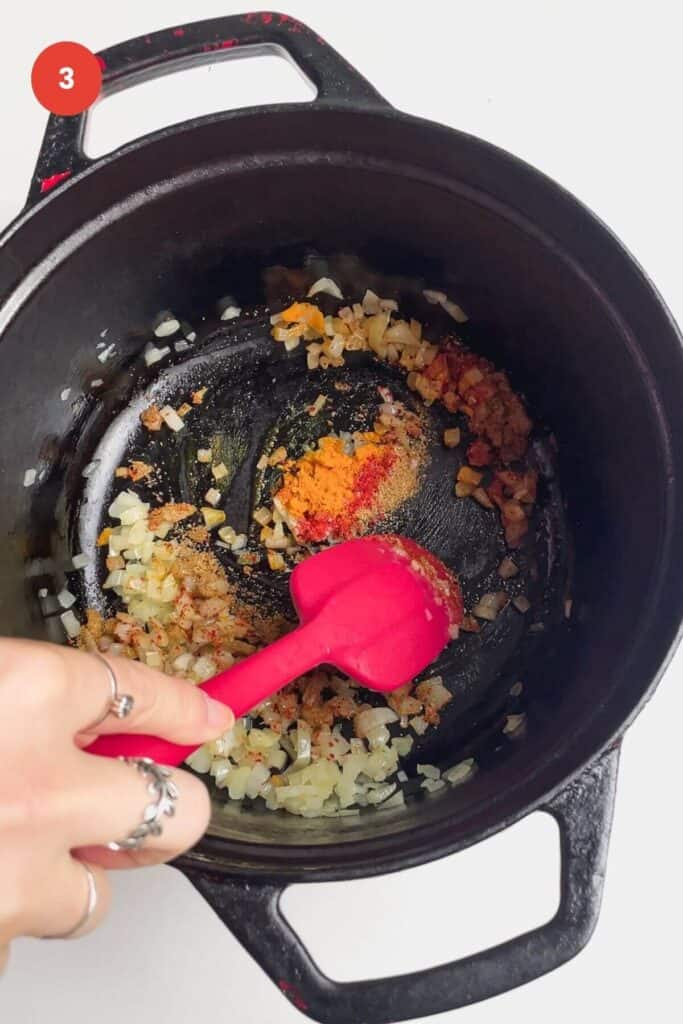Stirring diced onion and spices in saucepan.