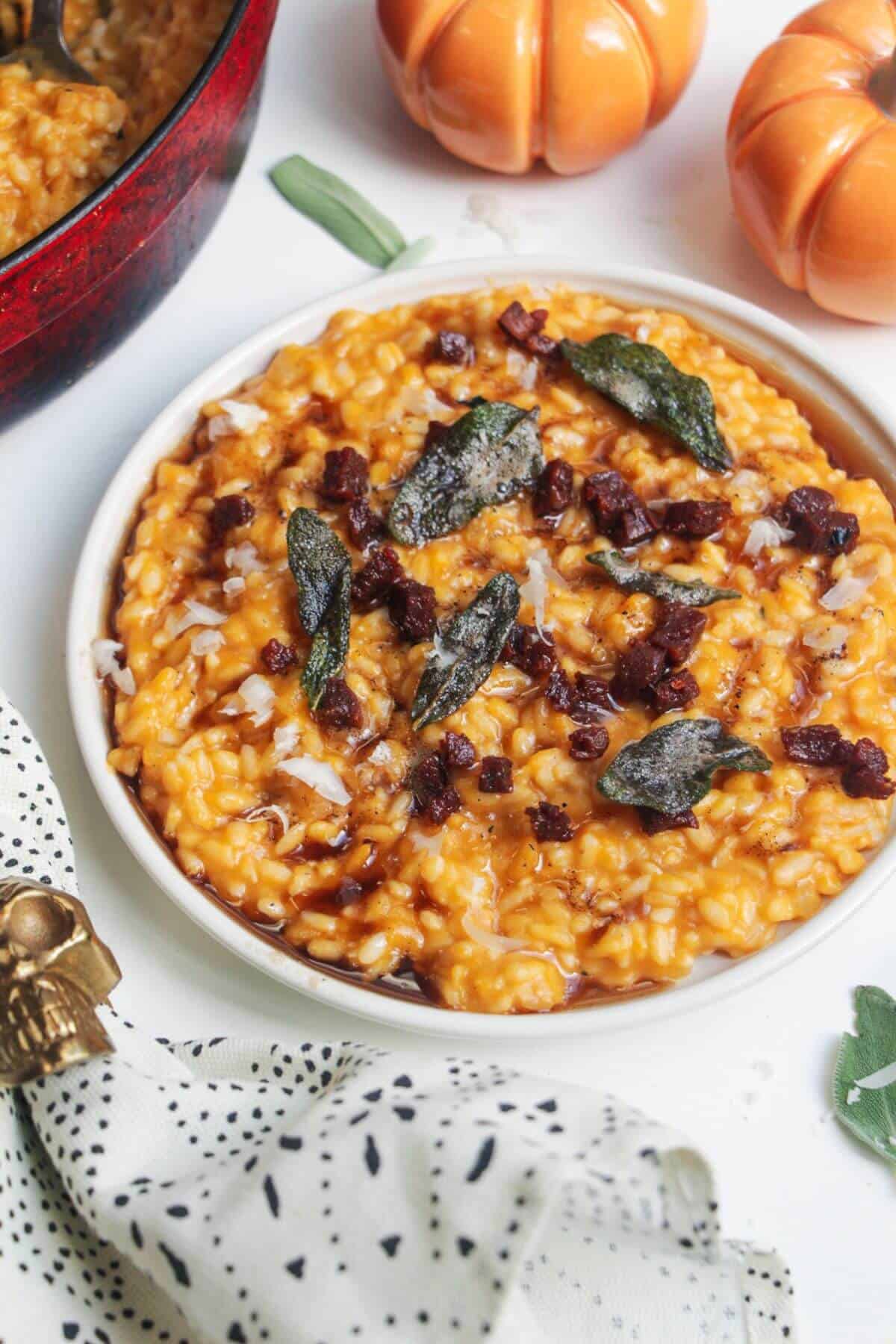 Butternut squash risotto on a small white plate, topped with sage brown butter and chorizo.
