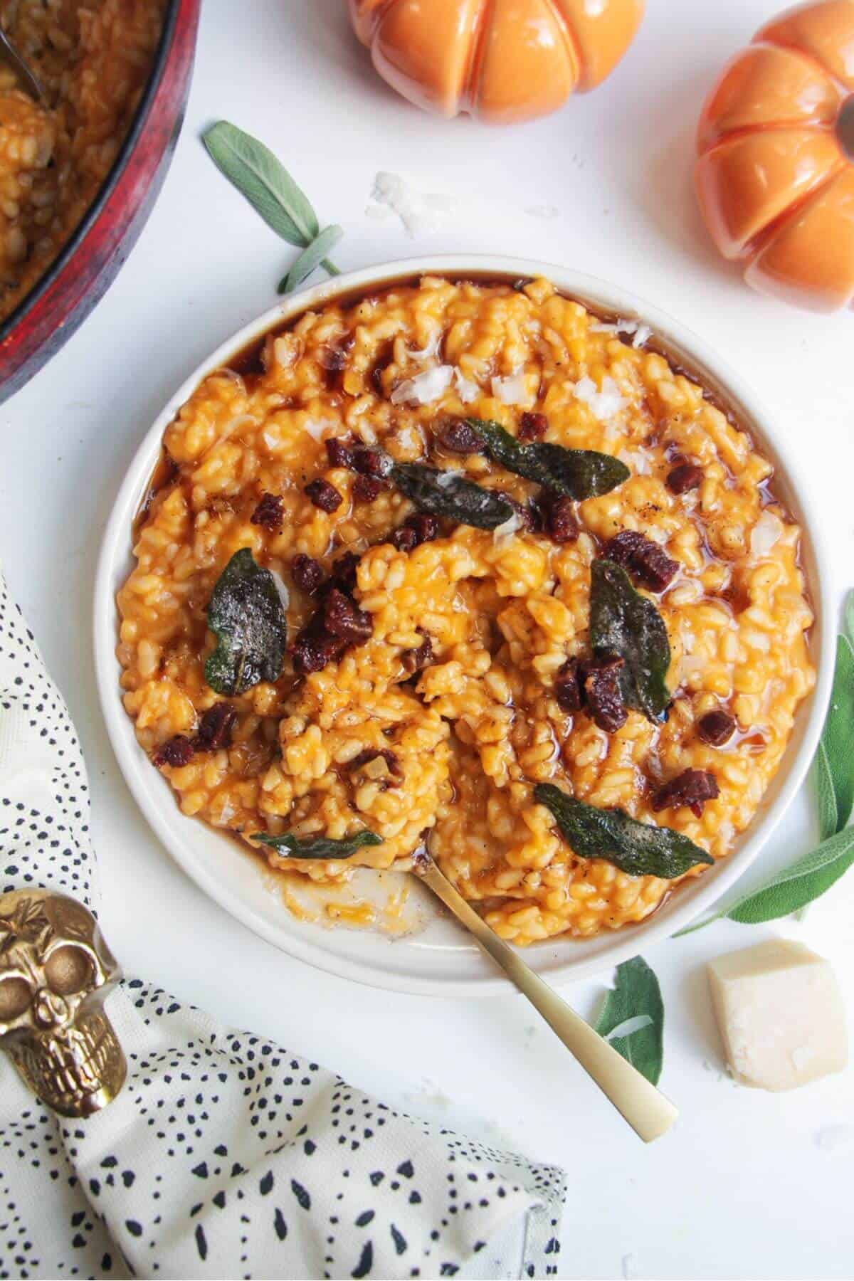 Butternut squash risotto on a small white plate, topped with sage brown butter and chorizo.