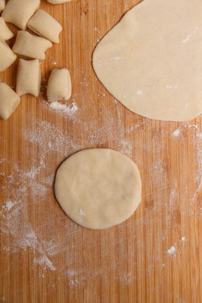 Small circle of dumpling dough on a large wooden board.