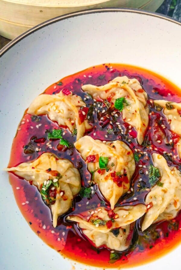 Dumplings in a bowl with red dipping sauce.