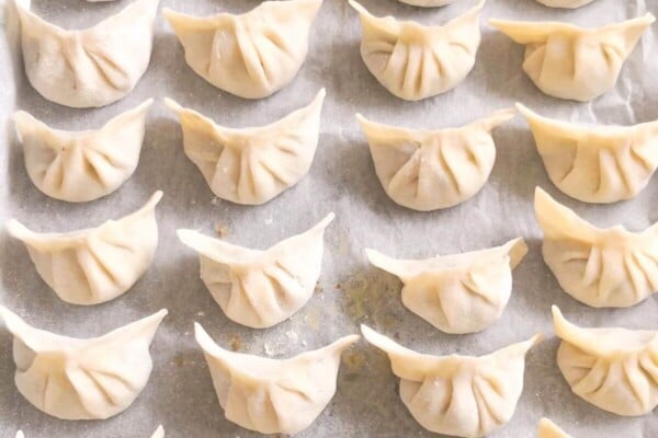 Dumplings laid out on a lined baking tray.