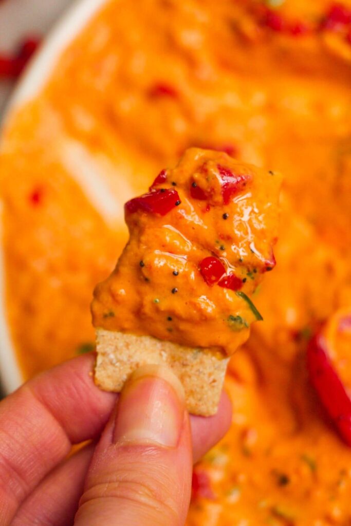 Close up of red pepper hummus on a cracker.