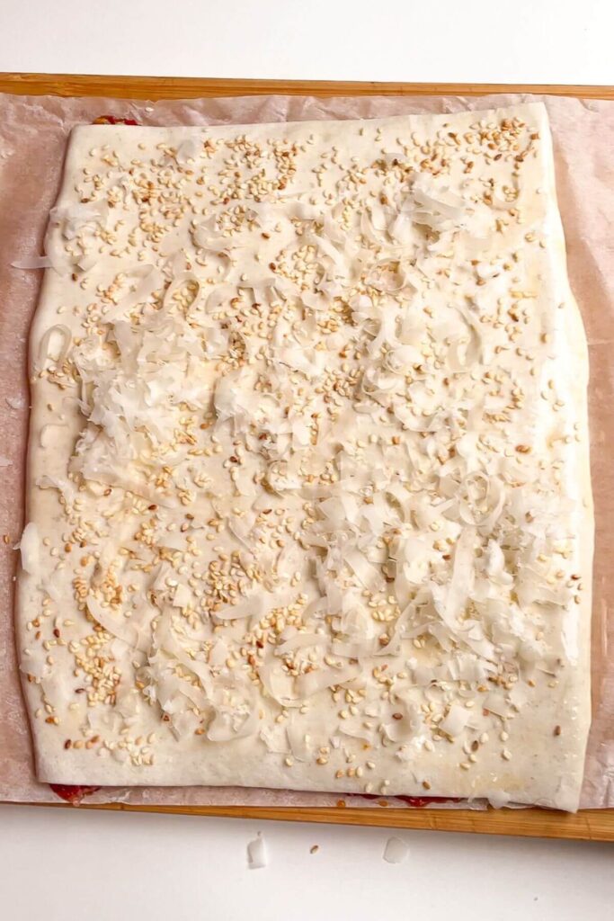 Grated parmesan and sesame seeds on top of puff pastry.