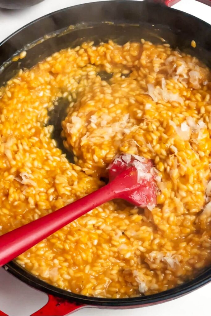 Stirring parmesan cheese into risotto in a pan.