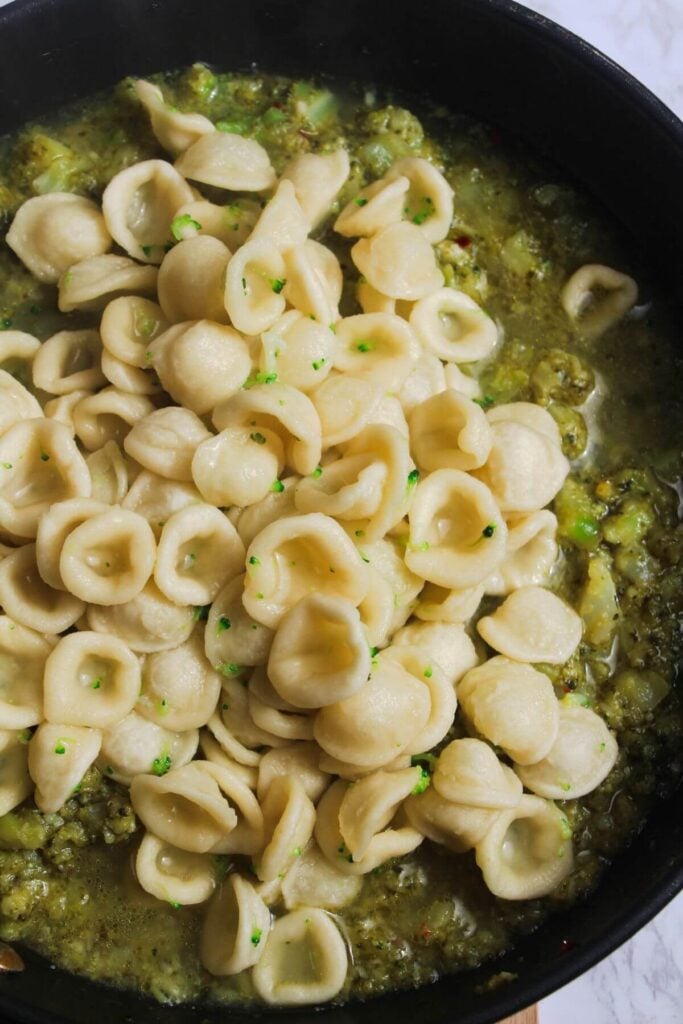 Pasta added to broccoli sauce in a large pan.