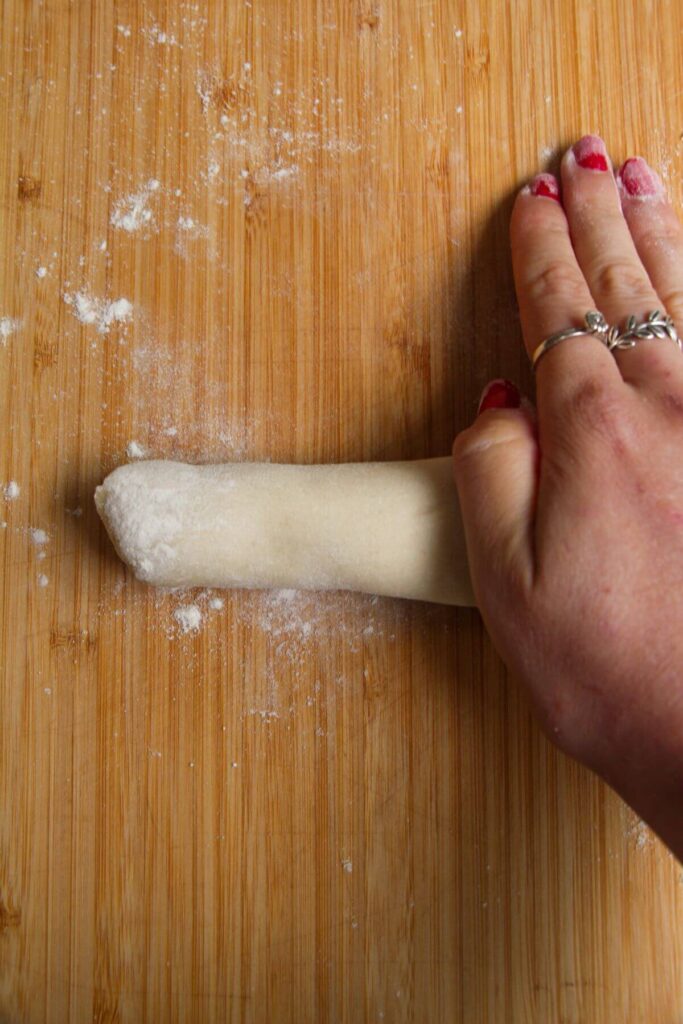 Hand rolling out a piece of dumpling dough.