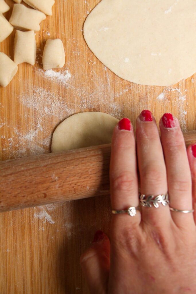 Hand using a rolling pin to roll out a small circle of dough.