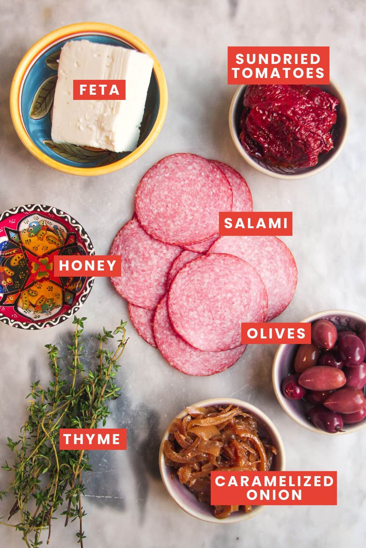 Ingredients for salami bites laid out on a marble surface and labelled.