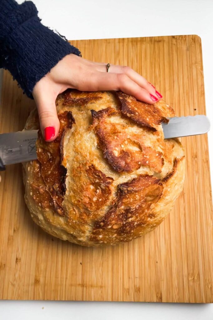 Slicing the top of a round loaf of bread off.