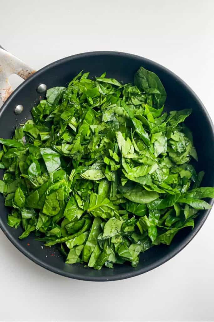 Spinach leaves in a small black pan.