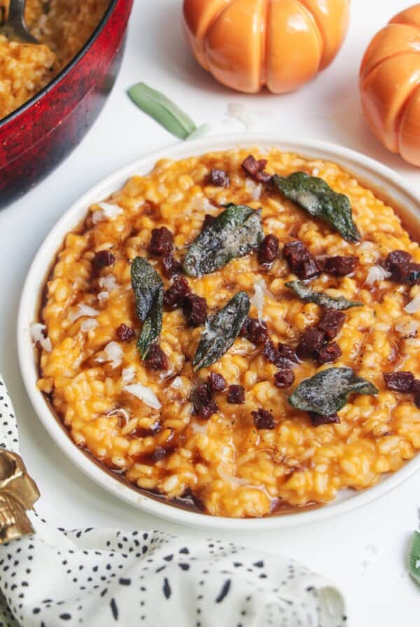 Butternut squash risotto on a small white plate, topped with sage brown butter and chorizo.