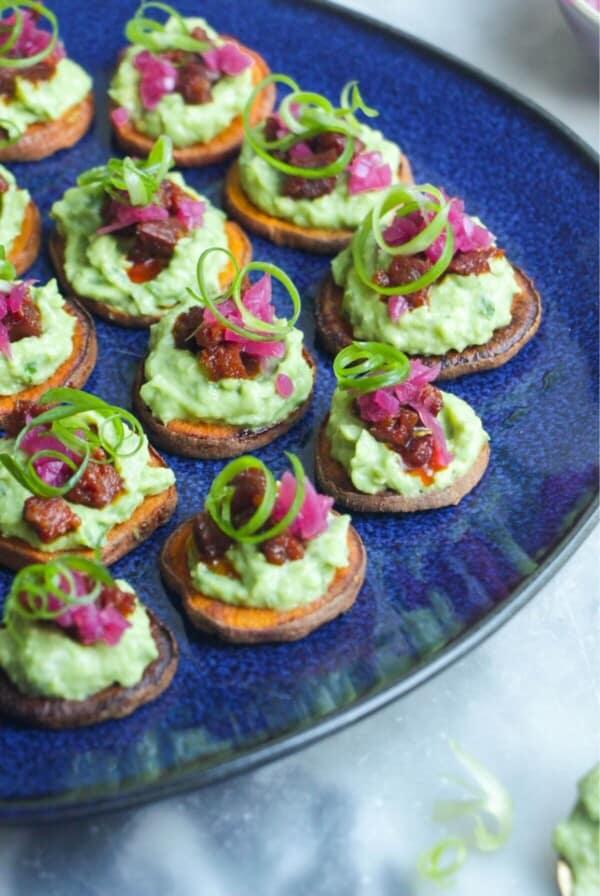 Loaded sweet potato bites on a large blue plate.