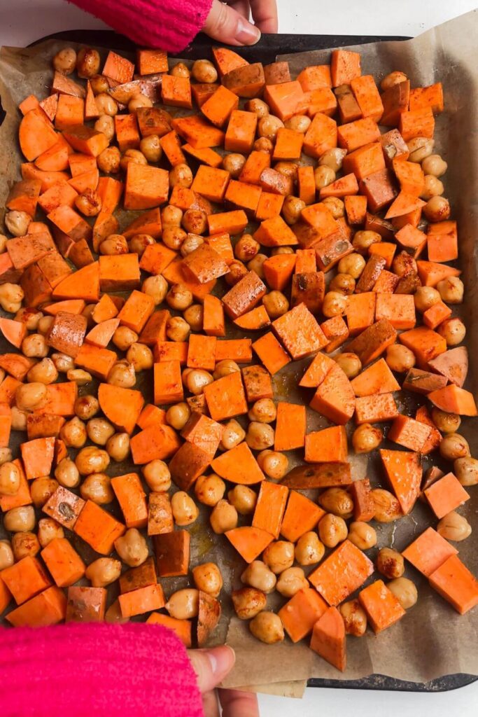 Diced sweet potatoes and chickpeas on a lined oven tray.