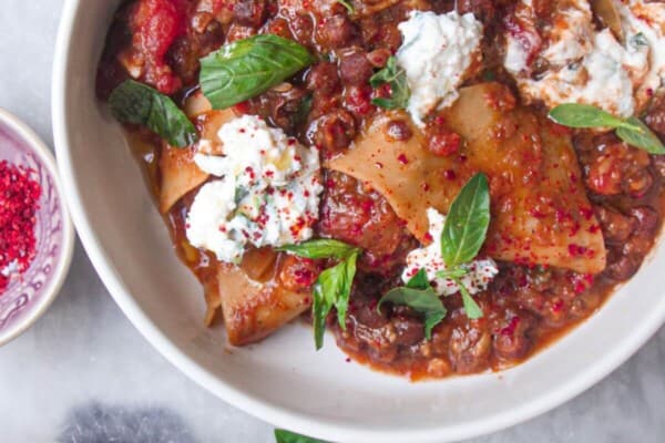 Two bowls of vegetarian lasagna soup, with ricotta on the side.