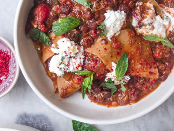 Two bowls of vegetarian lasagna soup, with ricotta on the side.