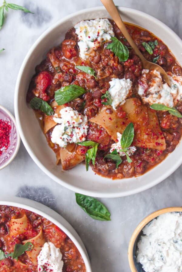 Two bowls of vegetarian lasagna soup, with ricotta on the side.