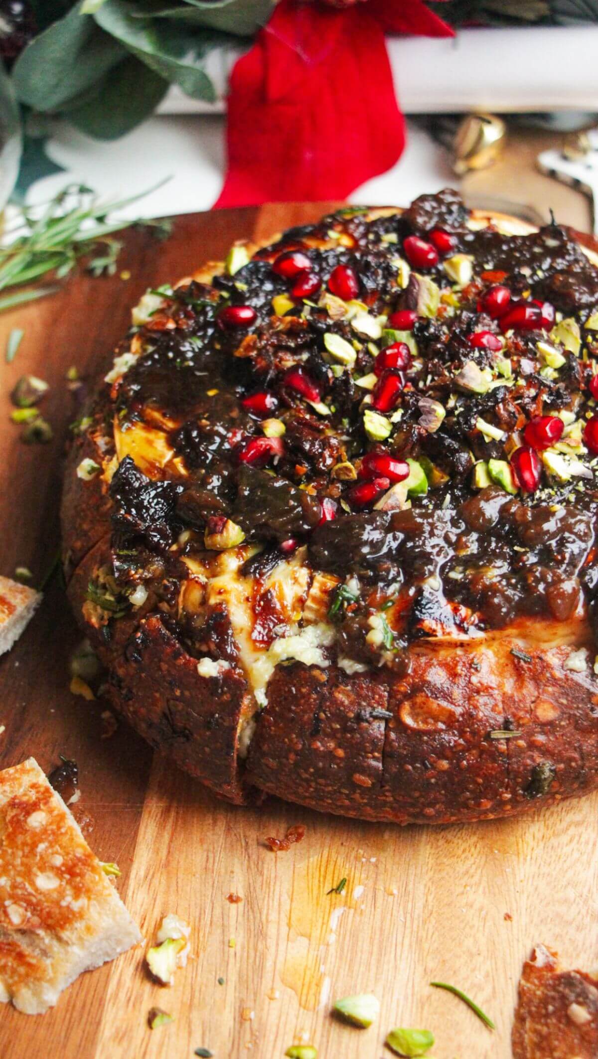 Baked brie in a loaf of bread, topped with fig jam and pomegranate seeds.