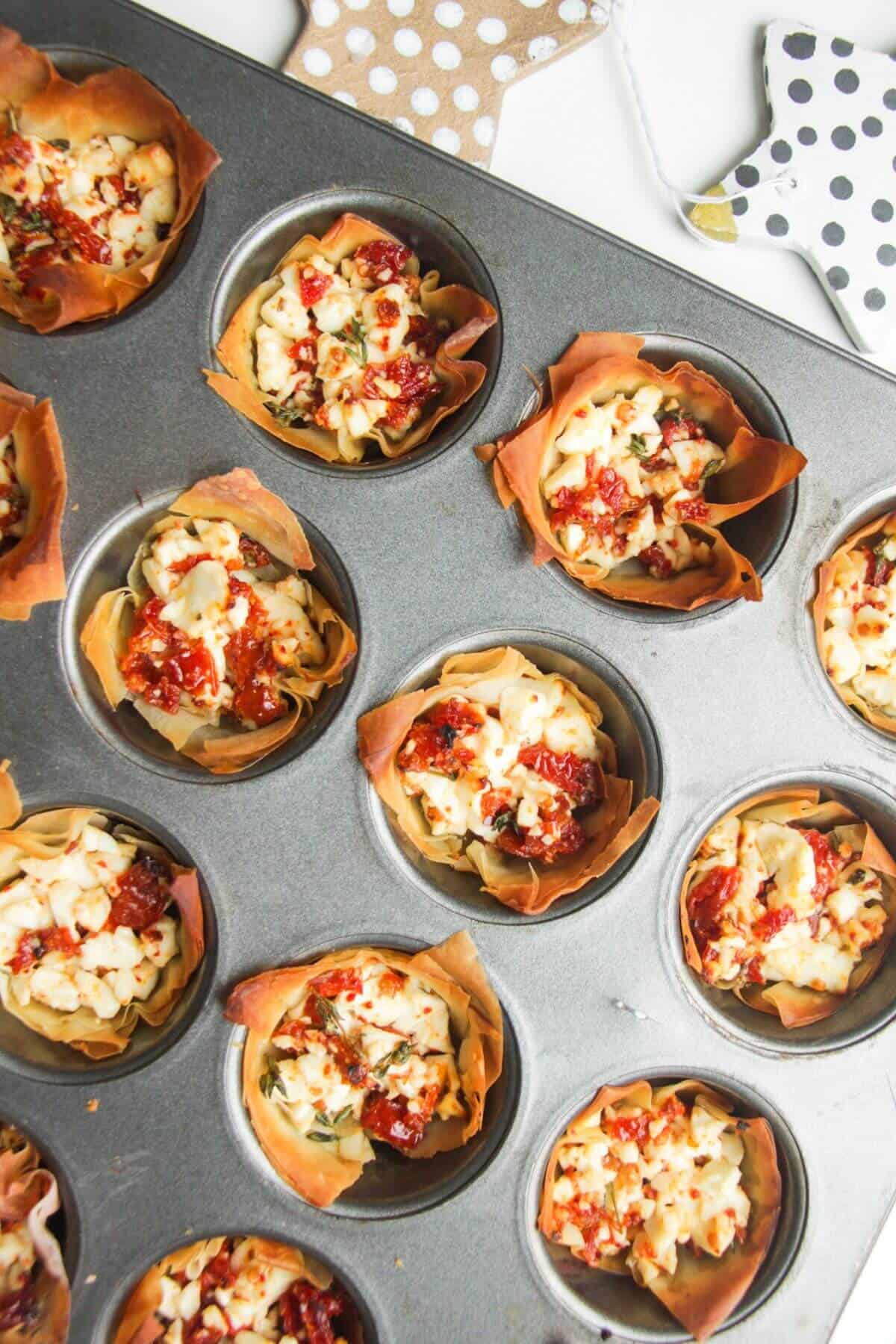 Close up of baked sundried tomato feta cups in a mini muffin tin.
