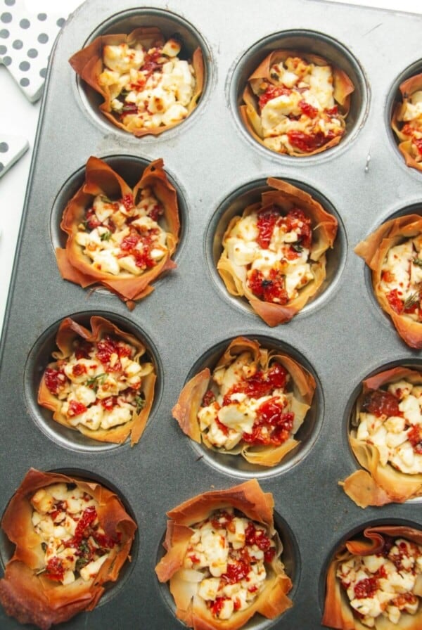 Close up of baked sundried tomato feta cups in a mini muffin tin.
