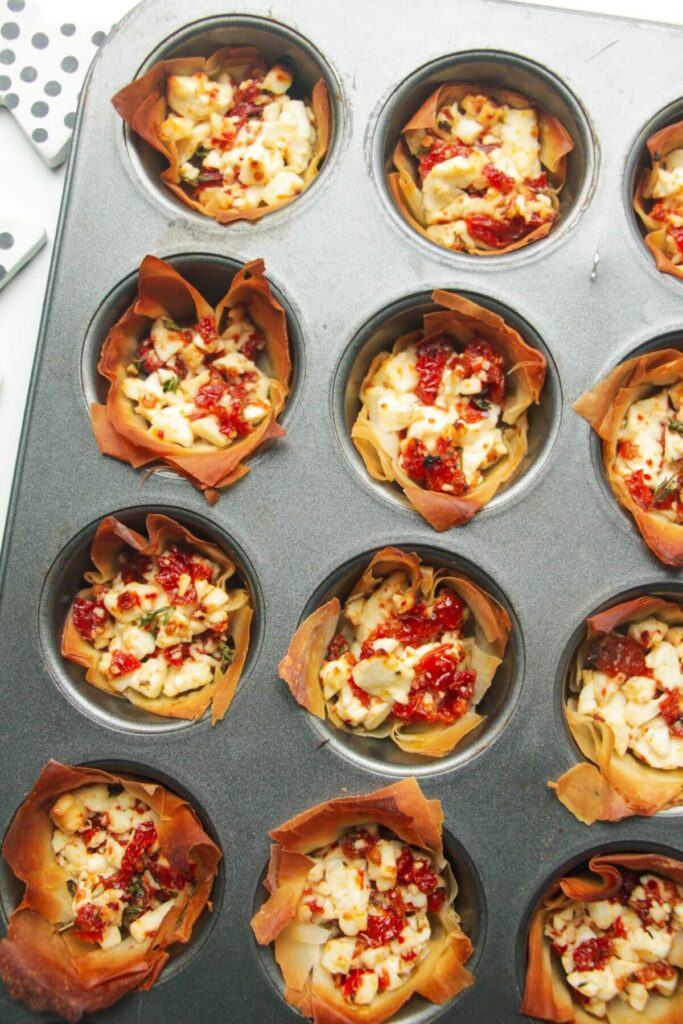 Close up of baked sundried tomato feta cups in a mini muffin tin.