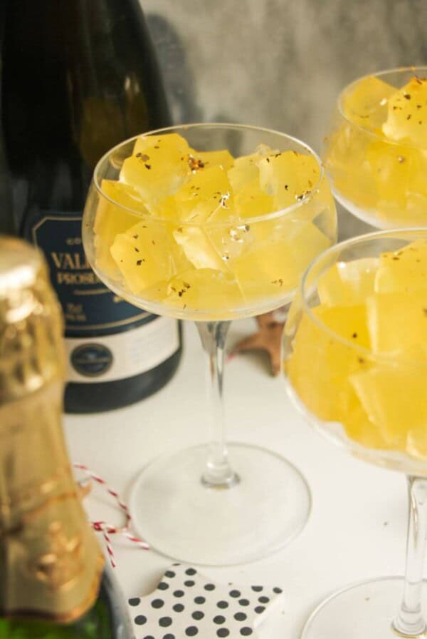 Three champagne coupes filled with jello cubes.