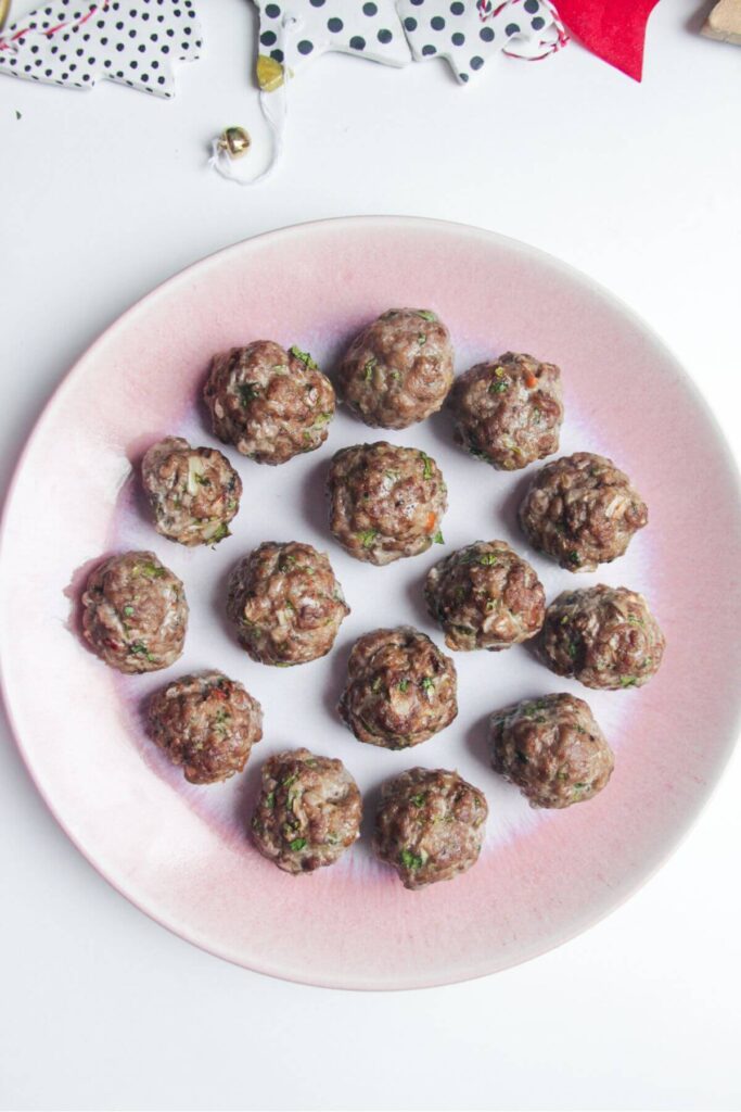 Cooked meatballs on a small pink plate.