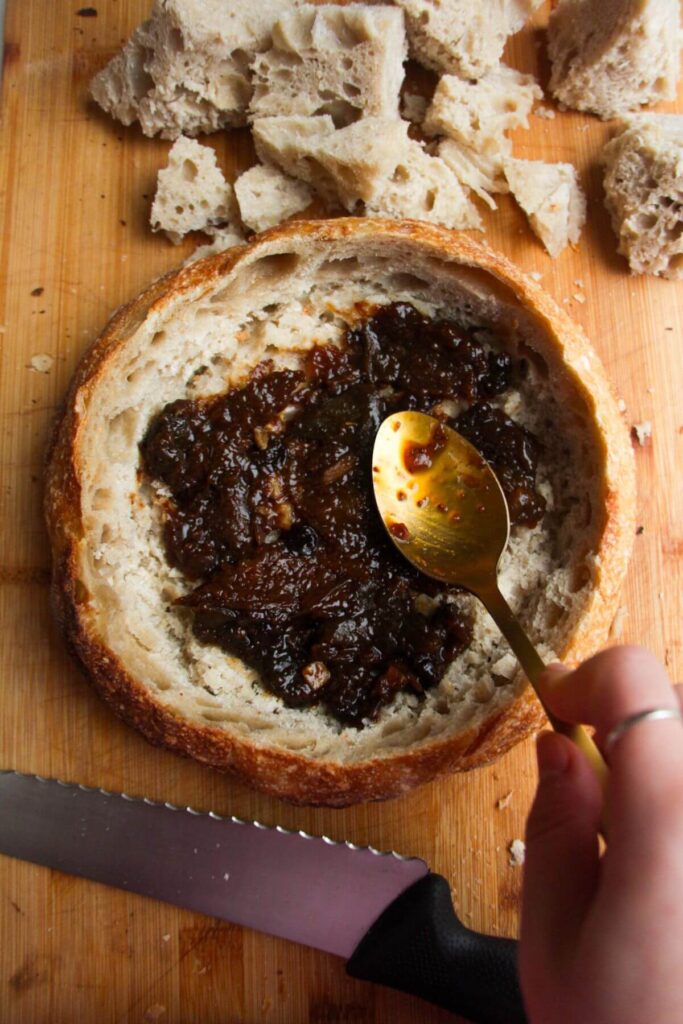Spooning fig jam into round loaf of bread.