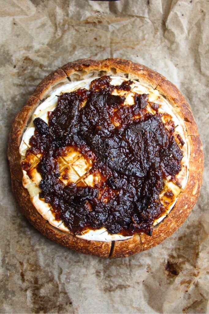 Fig jam on top of brie in a bread bowl.