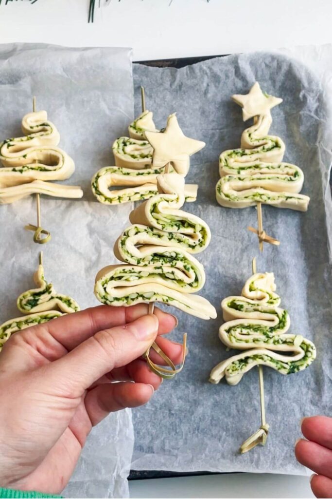 Holding up a skewered puff pastry Christmas tree.
