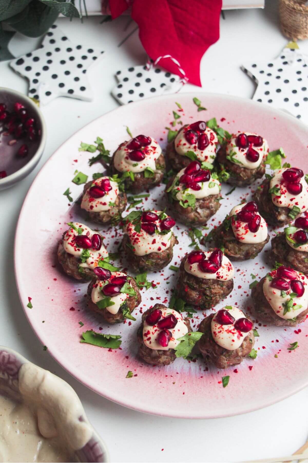 Decorated lamb meatballs on a small pink plate.