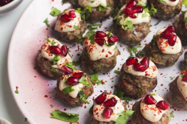 Decorated lamb meatballs on a small pink plate.