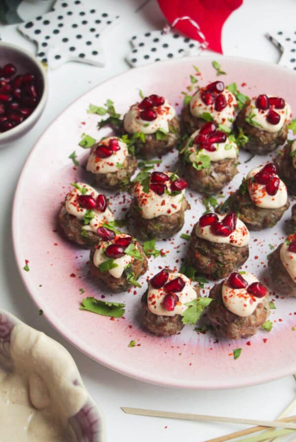 Decorated lamb meatballs on a small pink plate.